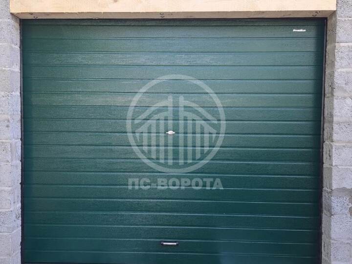 общий вид снаружи на установленные секционные подъемные ворота из зеленых сэндвич панелей с автоматикой
